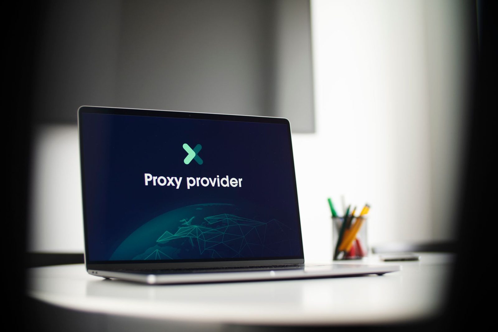 حاسوب محمول موضوع على طاولة بيضاء يعرض شاشة زرقاء مكتوب عليها «Proxy provider»