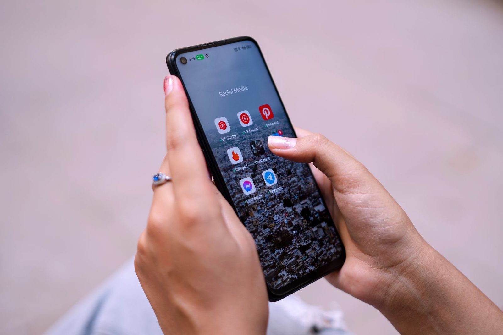 Main tenant un smartphone affichant un dossier d'applications de réseaux sociaux et de messagerie