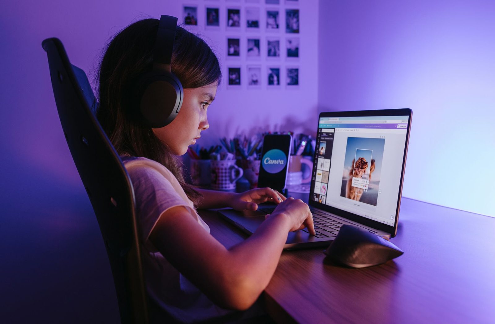 Ragazza con cuffie audio davanti a un computer portatile in una camera illuminata di viola