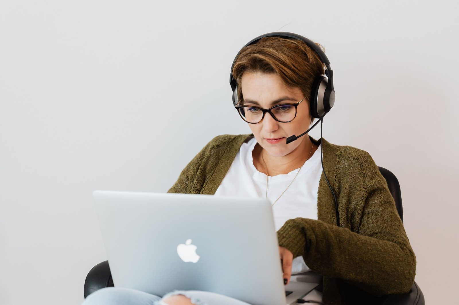 Femme avec casque-micro et lunettes devant un ordinateur portable, en pleine conversation en ligne
