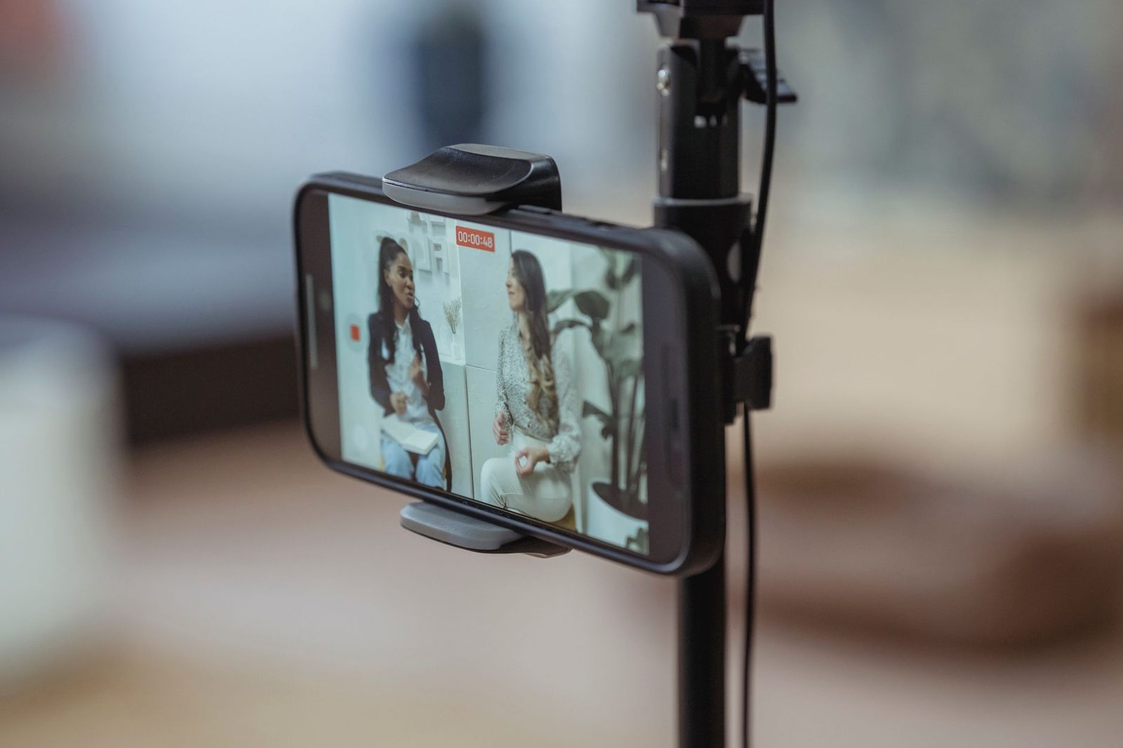 Smartphone fixé sur un trépied affichant un appel vidéo en écran partagé entre deux femmes qui discutent