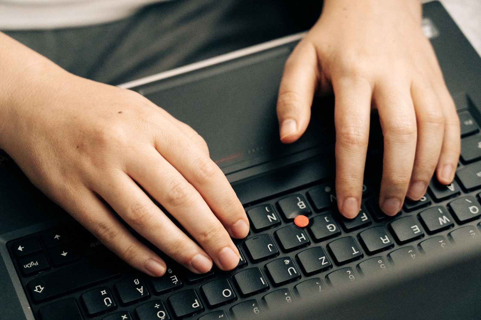 Gros plan de deux mains tapant sur le clavier noir d'un ordinateur portable