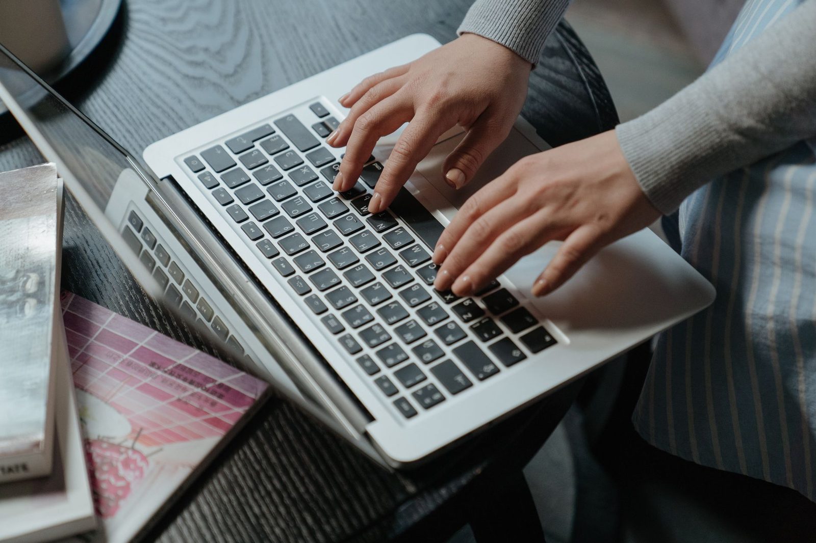 Mains d'une femme tapant sur le clavier d'un ordinateur portable posé sur une table en bois