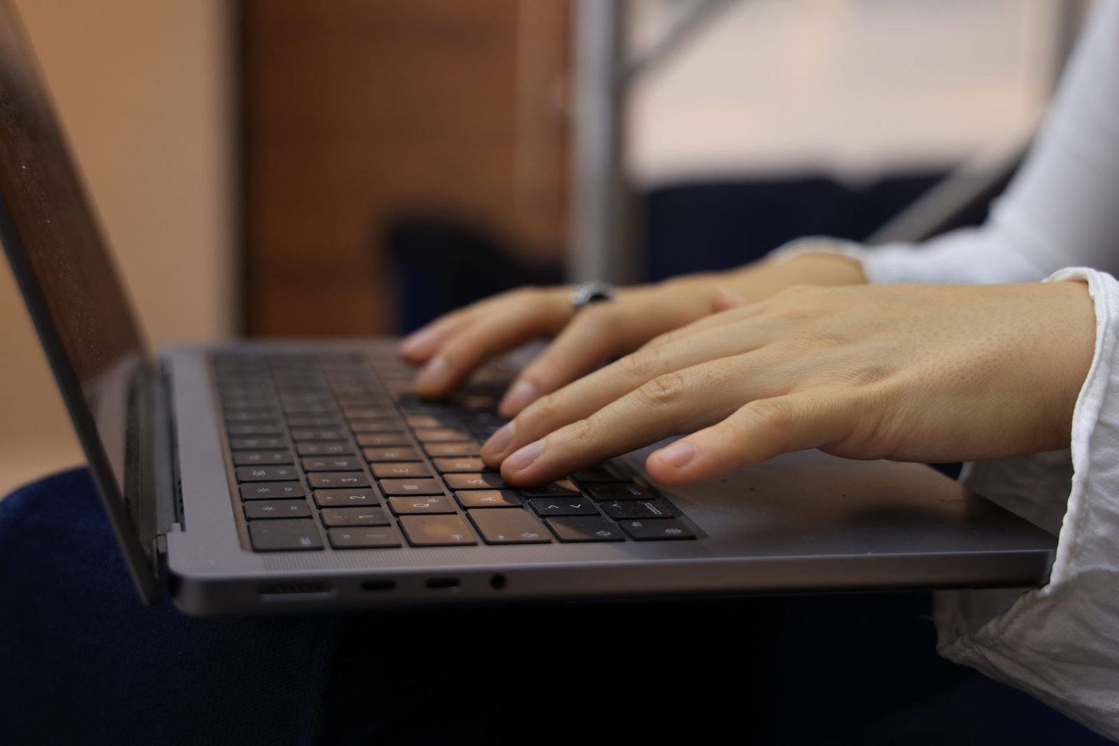 Gros plan sur les mains d'une femme tapant sur le clavier d'un ordinateur portable posé sur ses genoux